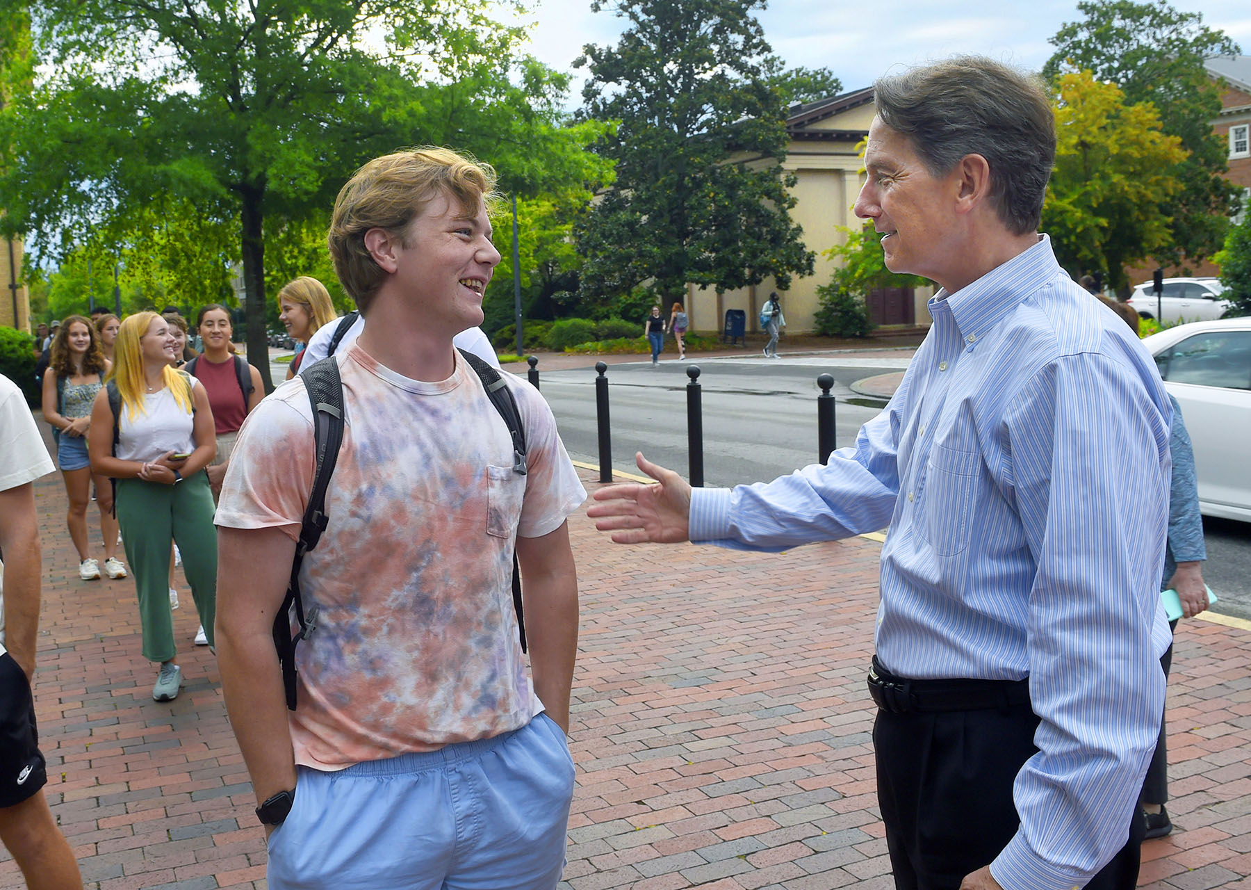 Dean Jim White meeting students as they line up to take a sip from the Old Well on the first day of classes. The time-honored tradition began in the 1980s and was promoted as a way to ensure academic success.